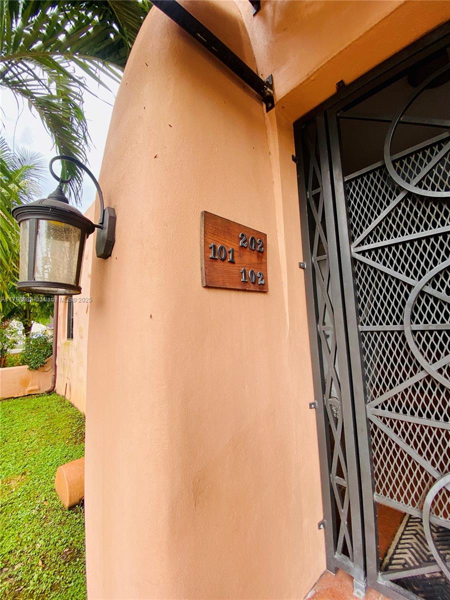 A wooden sign with unit numbers 101, 102, and 202 is mounted on a peach-colored wall — 200 Azure Way, Miami Springs FL 33166, MIAMI SPRINGS, FL