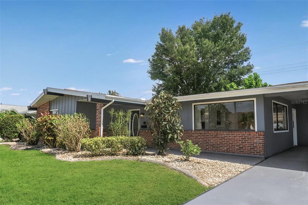 A single-story house with gray siding, a brick facade, and a front lawn — 806 OAKMONT AVENUE, SUN CITY CENTER, FL