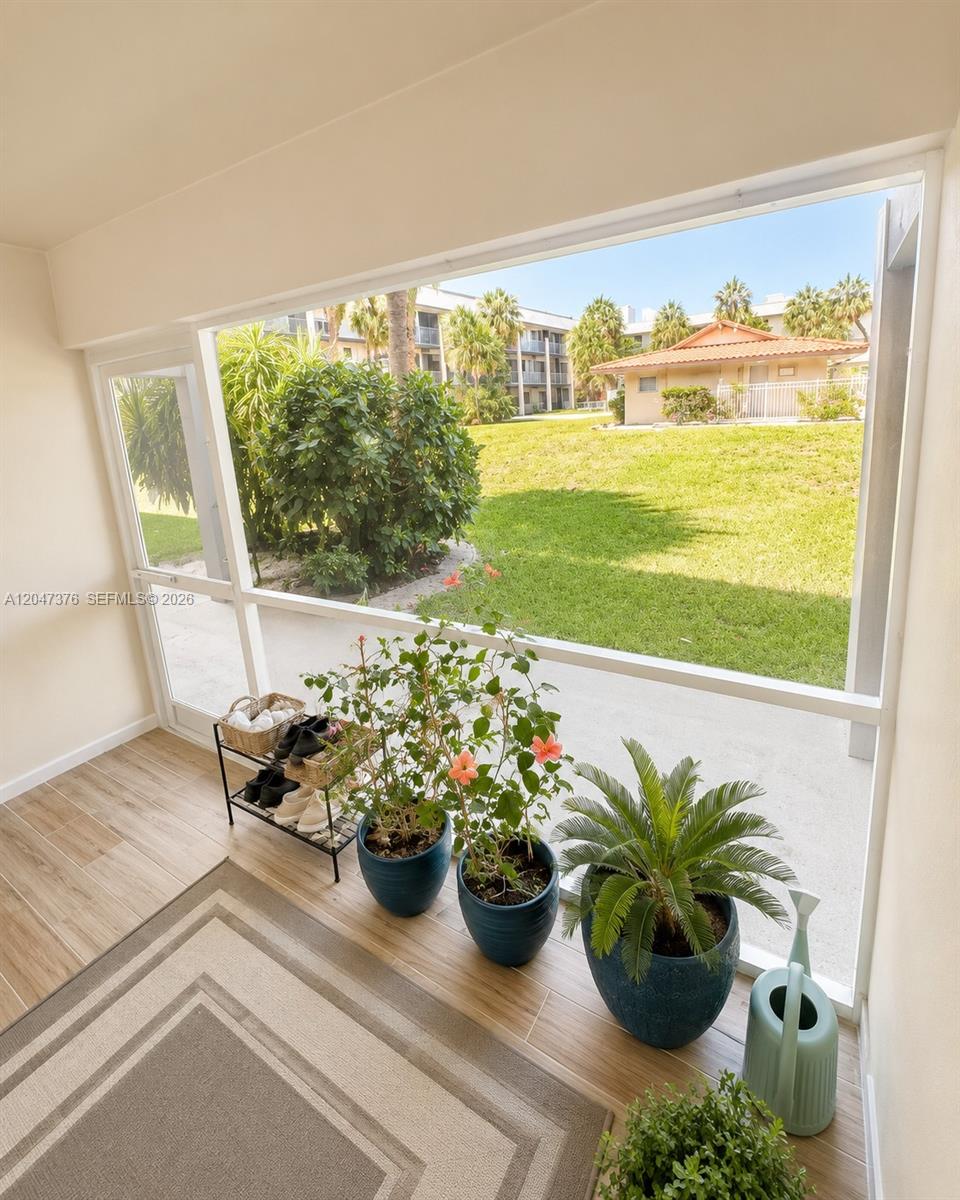 A screened-in patio features tile flooring, potted plants, and a view of a grassy courtyard — 270 E Layne Blvd # 110, Hallandale Beach FL 33009, HALLANDALE BEACH, FL