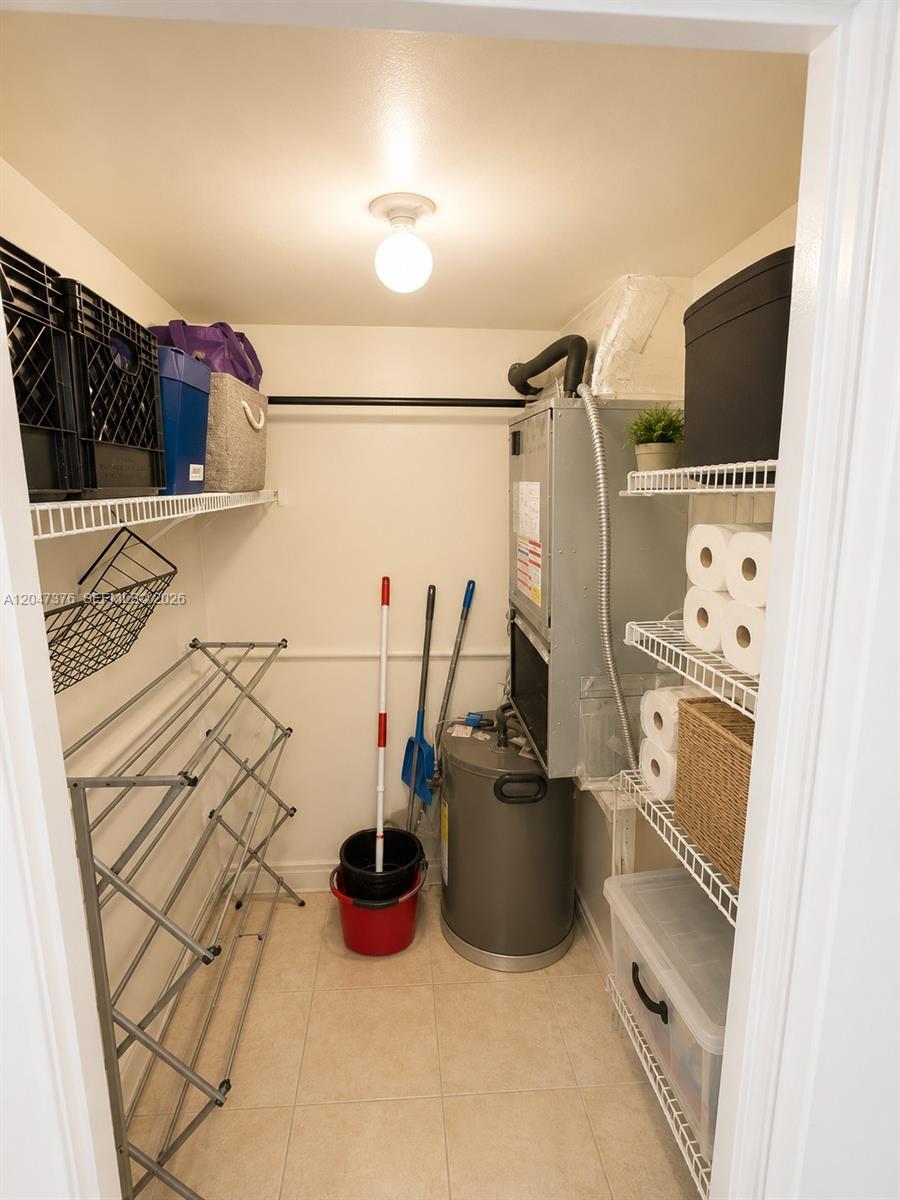 A utility closet contains a water heater, HVAC unit, shelving, and various household items — 270 E Layne Blvd # 110, Hallandale Beach FL 33009, HALLANDALE BEACH, FL