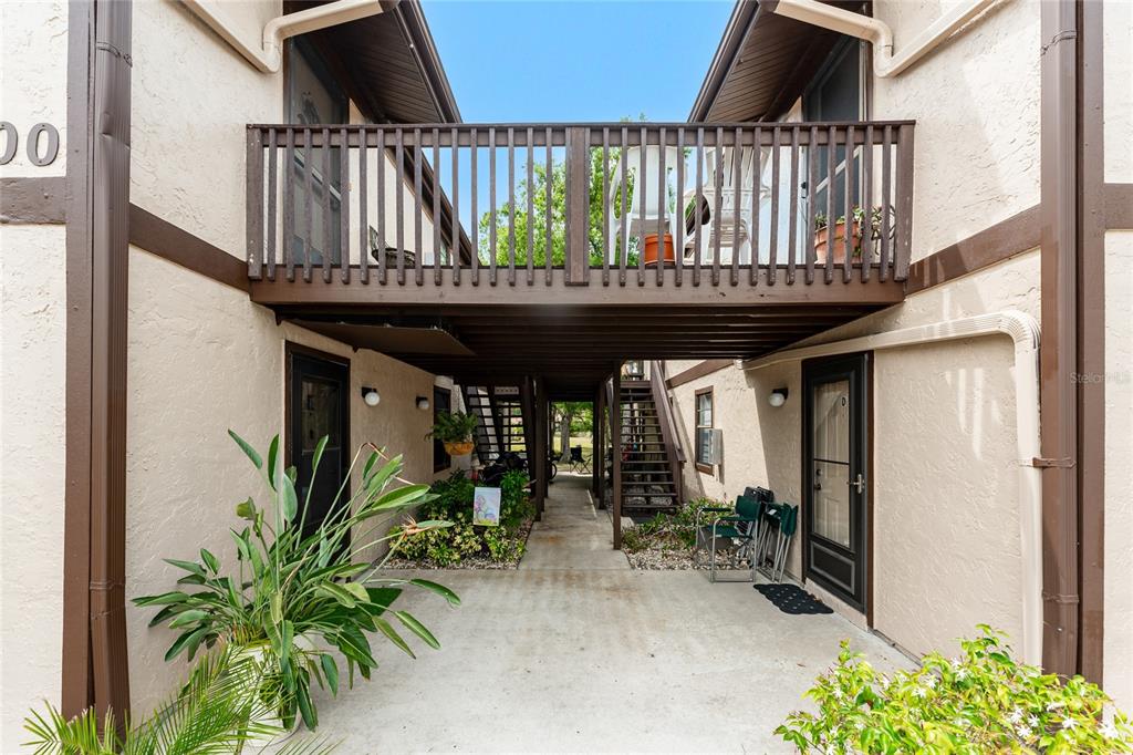 An exterior view shows a ground-level walkway between two building sections with an overhead balcony — 4022 BEAVER LANE UNIT 500C, PORT CHARLOTTE, FL