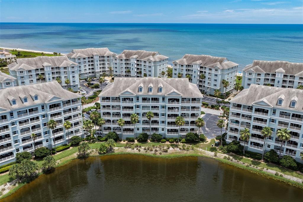 An aerial view shows multiple multi-story residential buildings situated along a coastline near a pond — 1100 CINNAMON BEACH WAY UNIT 1024, PALM COAST, FL