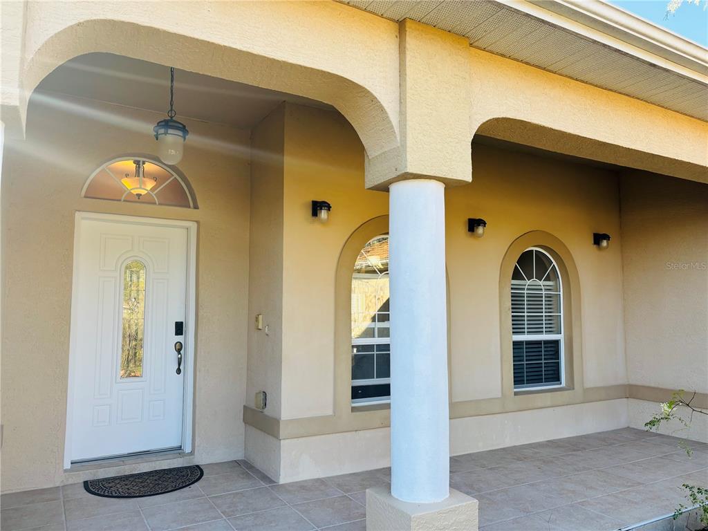 A covered front porch features a white door, arched windows, and a central support column — 3715 SW 127TH LANE ROAD, OCALA, FL