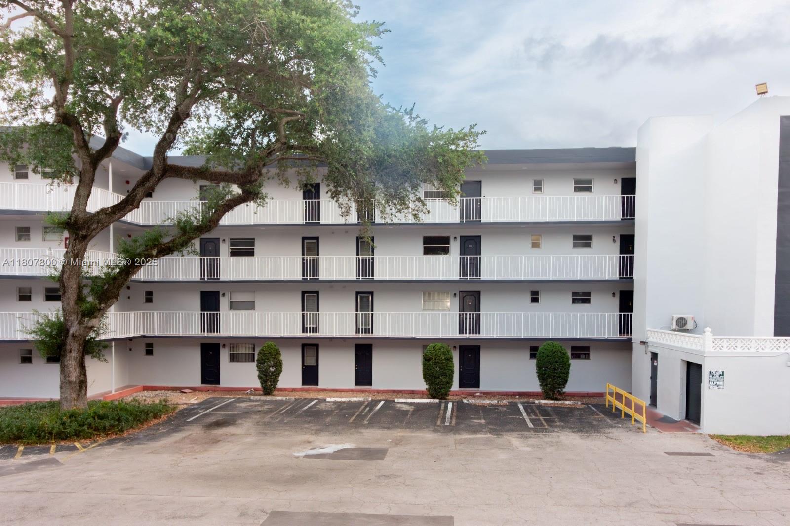 A four-story apartment building with exterior walkways and a parking lot in front — 447 NE 195th St # 217, Miami FL 33179, MIAMI, FL