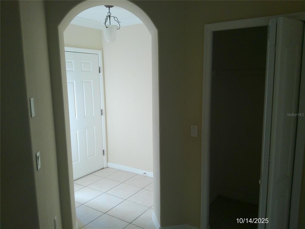 An arched doorway leads to a tiled entryway with a white door and a closet — 6376 SEDGEFORD DRIVE, LAKELAND, FL