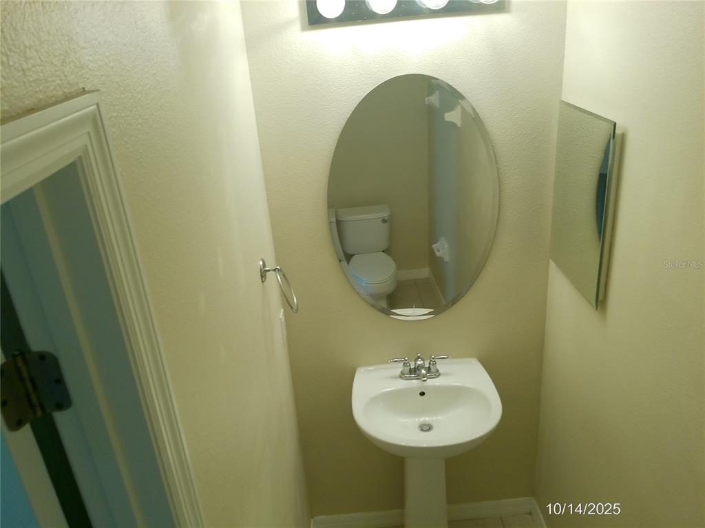 A small bathroom features a pedestal sink, an oval mirror, and a wall-mounted light fixture — 6376 SEDGEFORD DRIVE, LAKELAND, FL