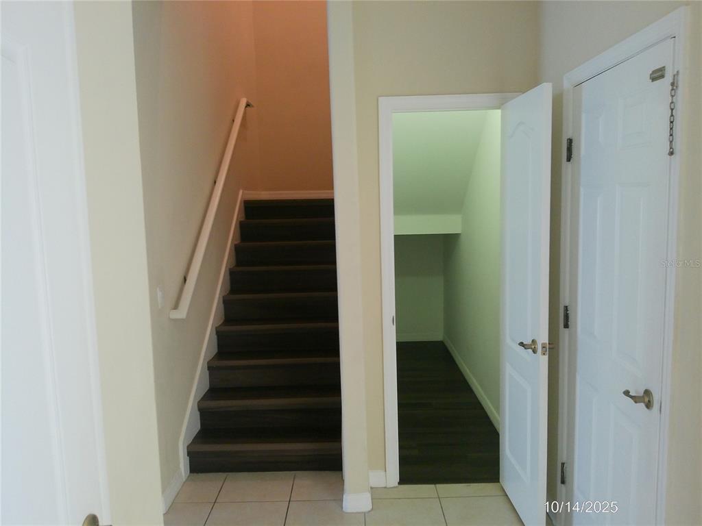 A staircase with dark wood treads sits beside an open under-stair storage closet — 6376 SEDGEFORD DRIVE, LAKELAND, FL