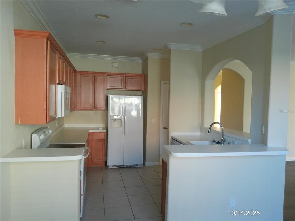 A kitchen with light wood cabinets, white appliances, tile flooring, and a breakfast bar — 6376 SEDGEFORD DRIVE, LAKELAND, FL