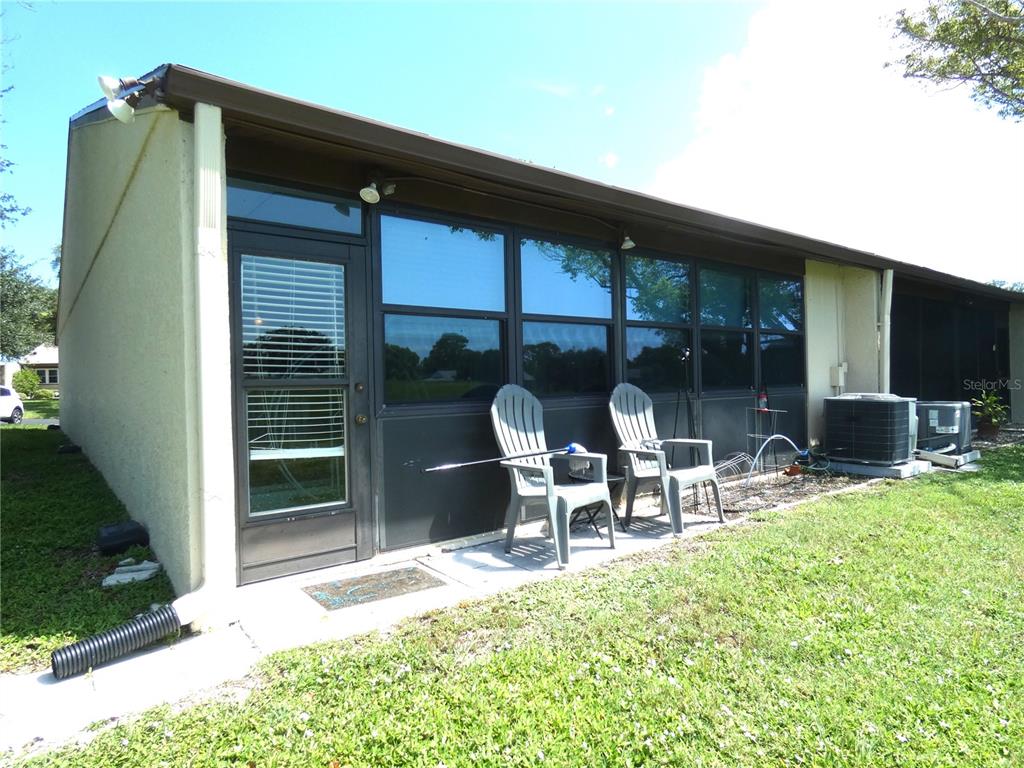 An exterior view of a house with a glass door, windows, and two plastic chairs — 11231 DOLLAR LAKE DRIVE UNIT 6, PORT RICHEY, FL