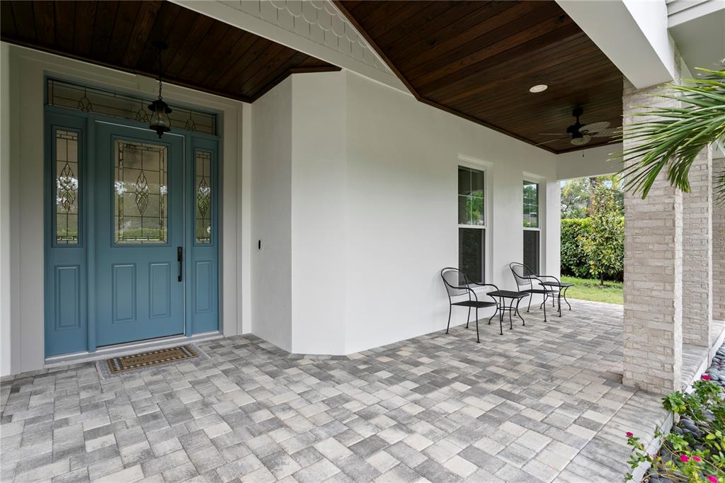 A covered front porch features a blue door, white walls, and gray paver flooring — 1009 S MORRISON COURT, TAMPA, FL
