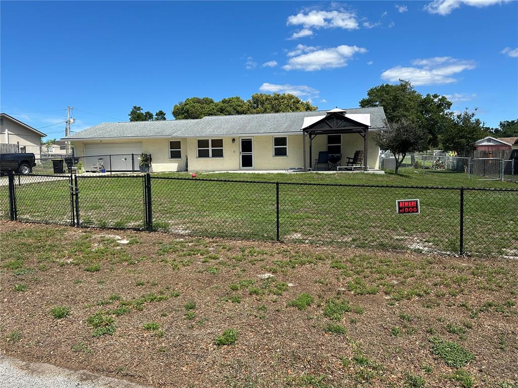 A single-story yellow house with a garage and a fenced yard under a blue sky — 7411 ORANGE CREST CIRCLE, LAKELAND, FL