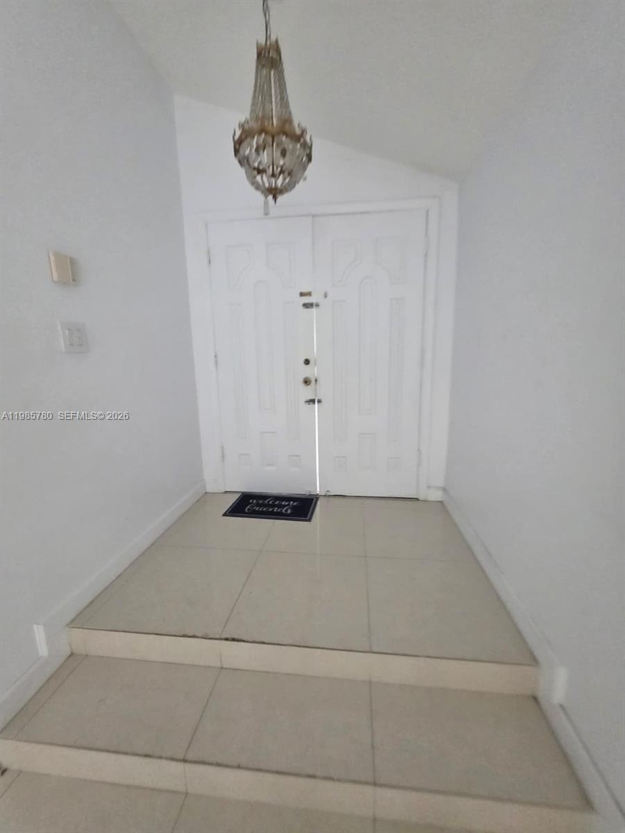 An entryway features a chandelier, double doors, and two steps leading up to the entrance — 710 SW 99th Ct Cir, Miami FL 33174, MIAMI, FL
