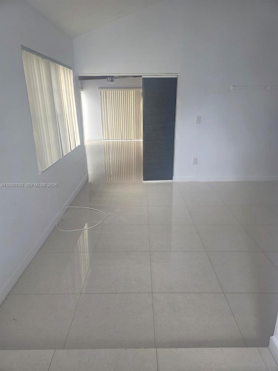 A bright, empty room features white walls, large light-colored floor tiles, and vertical window blinds — 710 SW 99th Ct Cir, Miami FL 33174, MIAMI, FL