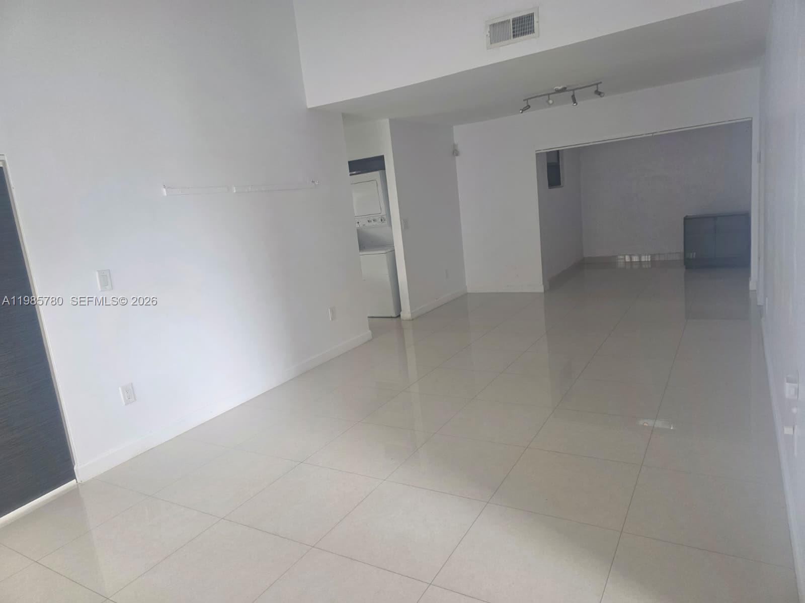 An open-concept living area features white walls, large light-colored floor tiles, and a laundry closet — 710 SW 99th Ct Cir, Miami FL 33174, MIAMI, FL