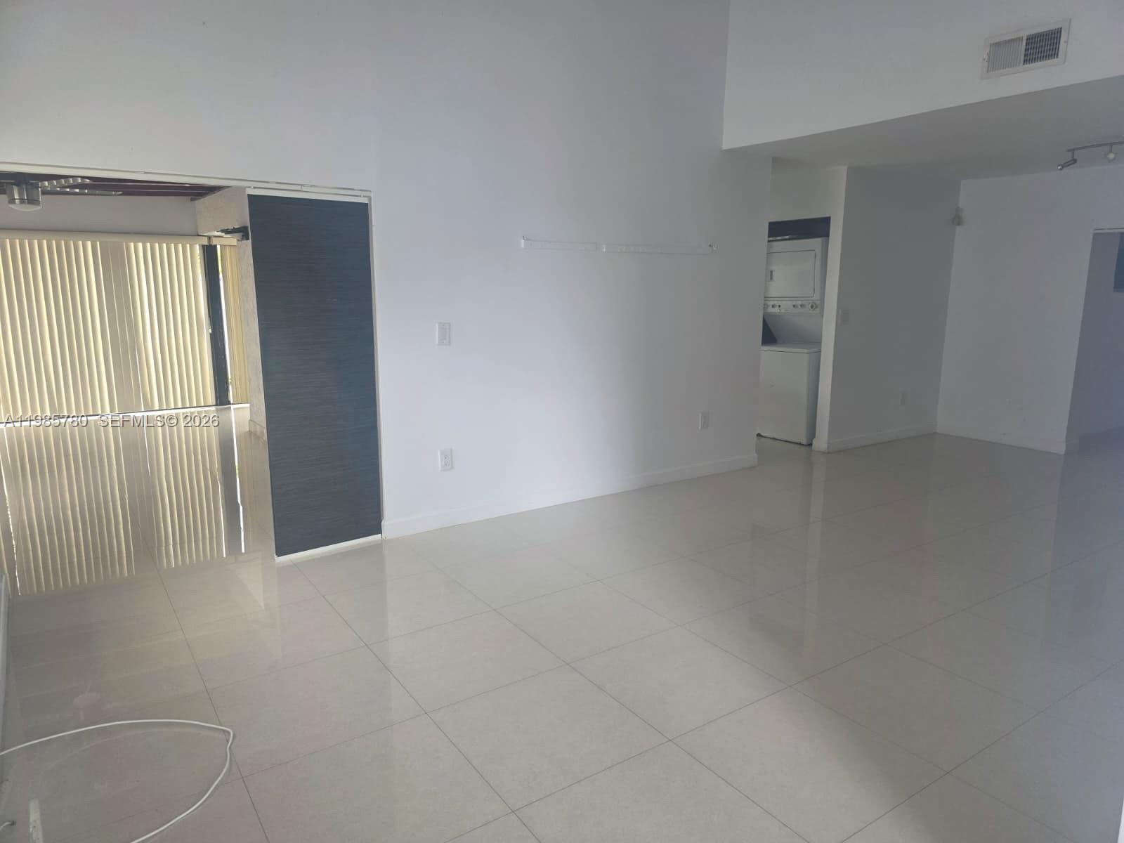 An empty room with white walls, light tile flooring, and a laundry closet — 710 SW 99th Ct Cir, Miami FL 33174, MIAMI, FL