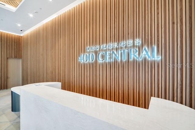 A modern lobby features a white reception desk against a wall of vertical wood slats — 400 CENTRAL AVENUE UNIT 1009, ST PETERSBURG, FL