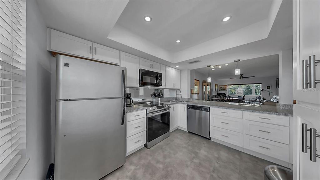 A kitchen features white cabinets, stainless steel appliances, and a gray tiled floor — 7321 CENTRAL AVENUE UNIT 307, ST PETERSBURG, FL