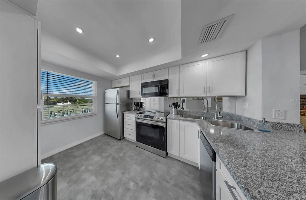 A kitchen with white cabinets, stainless steel appliances, granite countertops, and a window — 7321 CENTRAL AVENUE UNIT 307, ST PETERSBURG, FL