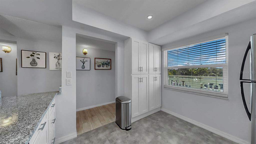A kitchen area features white cabinetry, granite countertops, a stainless steel trash can, and a window — 7321 CENTRAL AVENUE UNIT 307, ST PETERSBURG, FL
