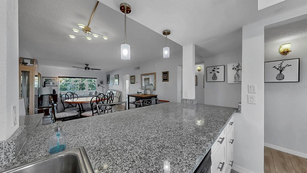 A kitchen with granite countertops overlooks a dining area and living room — 7321 CENTRAL AVENUE UNIT 307, ST PETERSBURG, FL