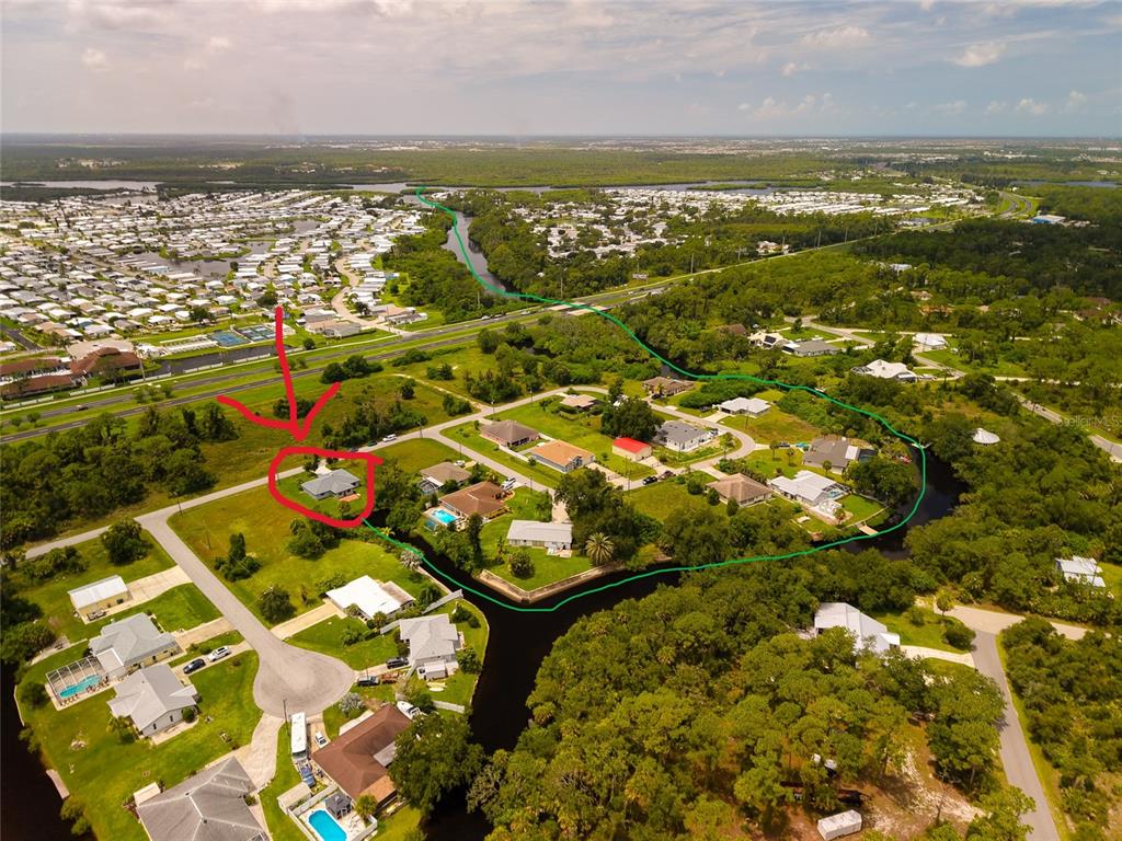 This aerial view shows a residential neighborhood with a canal and a highlighted house — 11910 SARAGOSSA LANE, NORTH PORT, FL
