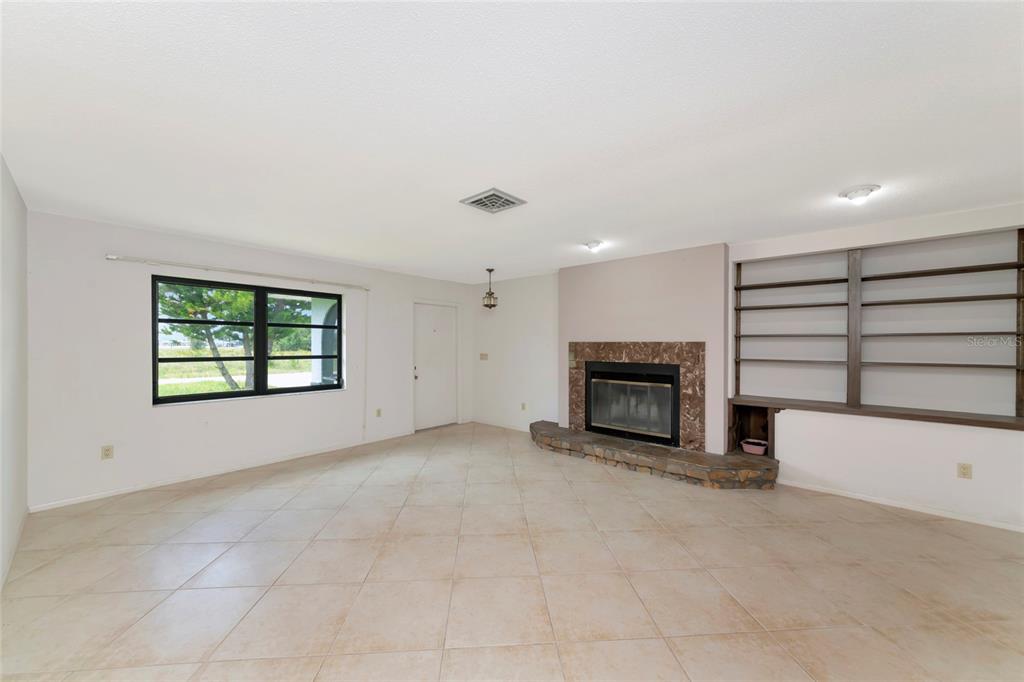A living room features light tile flooring, a stone fireplace, and built-in wooden shelving — 11910 SARAGOSSA LANE, NORTH PORT, FL