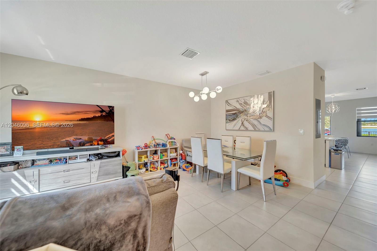A living and dining area features tile flooring, a television console, and a glass-topped table — 11295 W 34th Way, Hialeah FL 33018, HIALEAH, FL