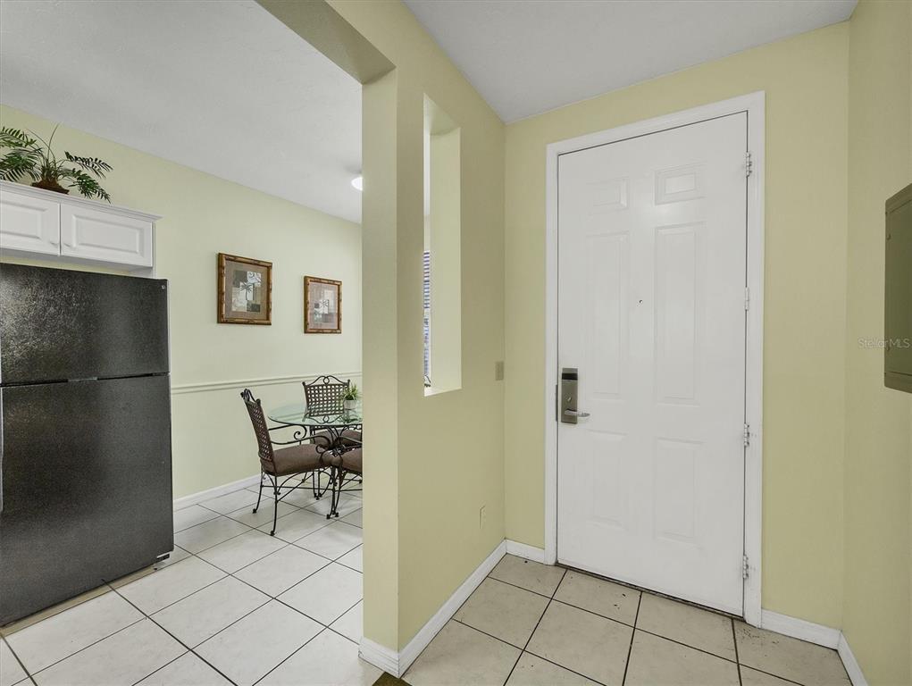An entryway with tile flooring leads to a dining area with a glass table — 3506 54TH DRIVE W UNIT 104, BRADENTON, FL