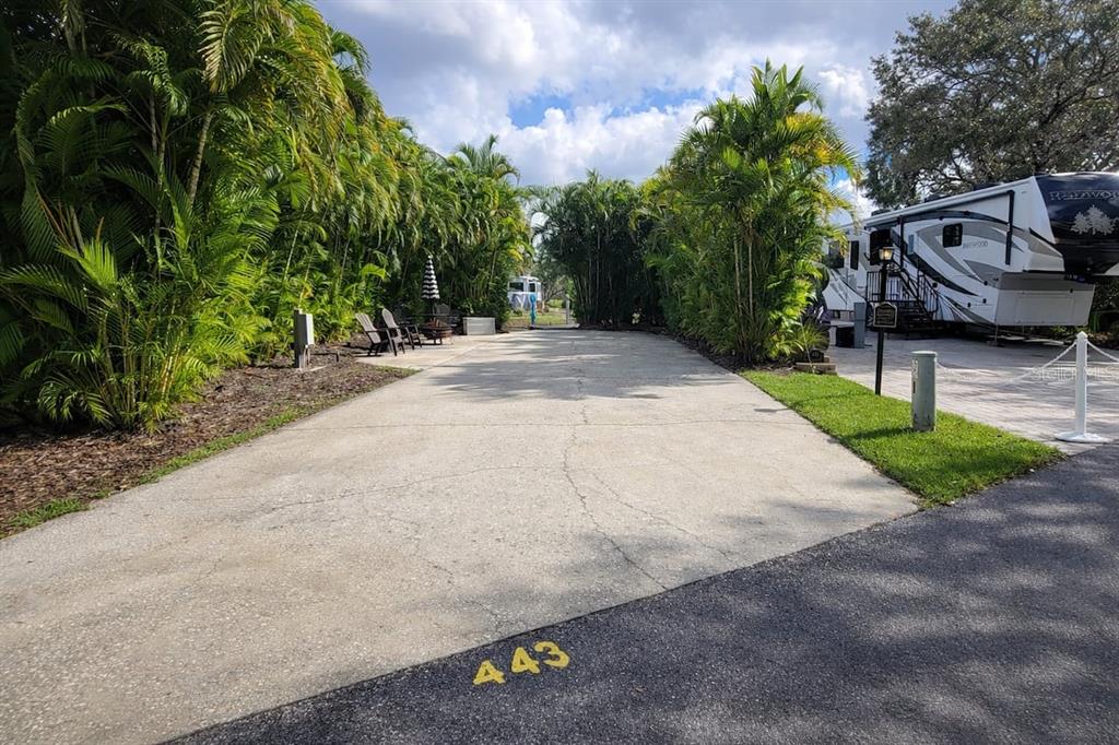 A paved driveway at an RV site features lush landscaping and a parked recreational vehicle — 443 WATERWAY DRIVE, LAKE WALES, FL