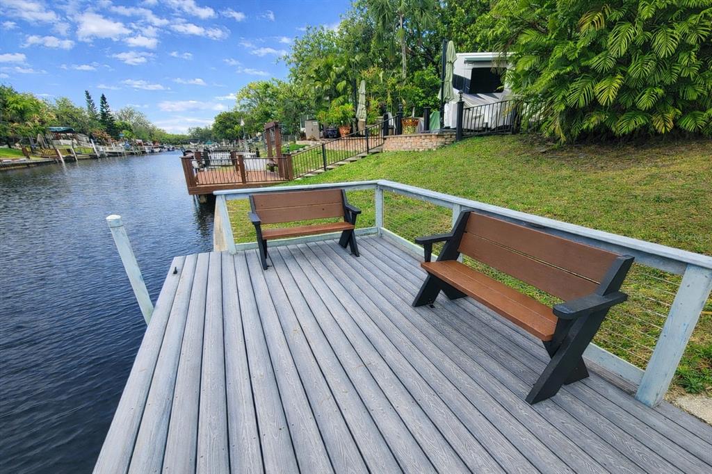 A wooden deck with two benches overlooks a canal lined with trees and other docks — 443 WATERWAY DRIVE, LAKE WALES, FL