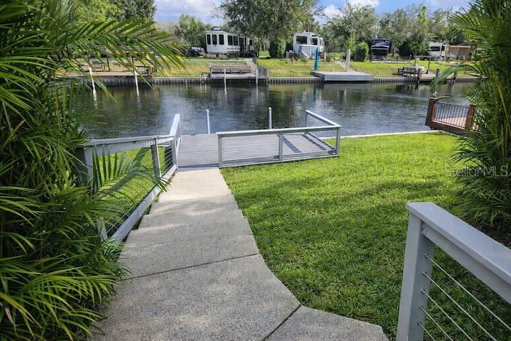 A concrete walkway leads down to a wooden dock overlooking a canal with parked RVs — 443 WATERWAY DRIVE, LAKE WALES, FL