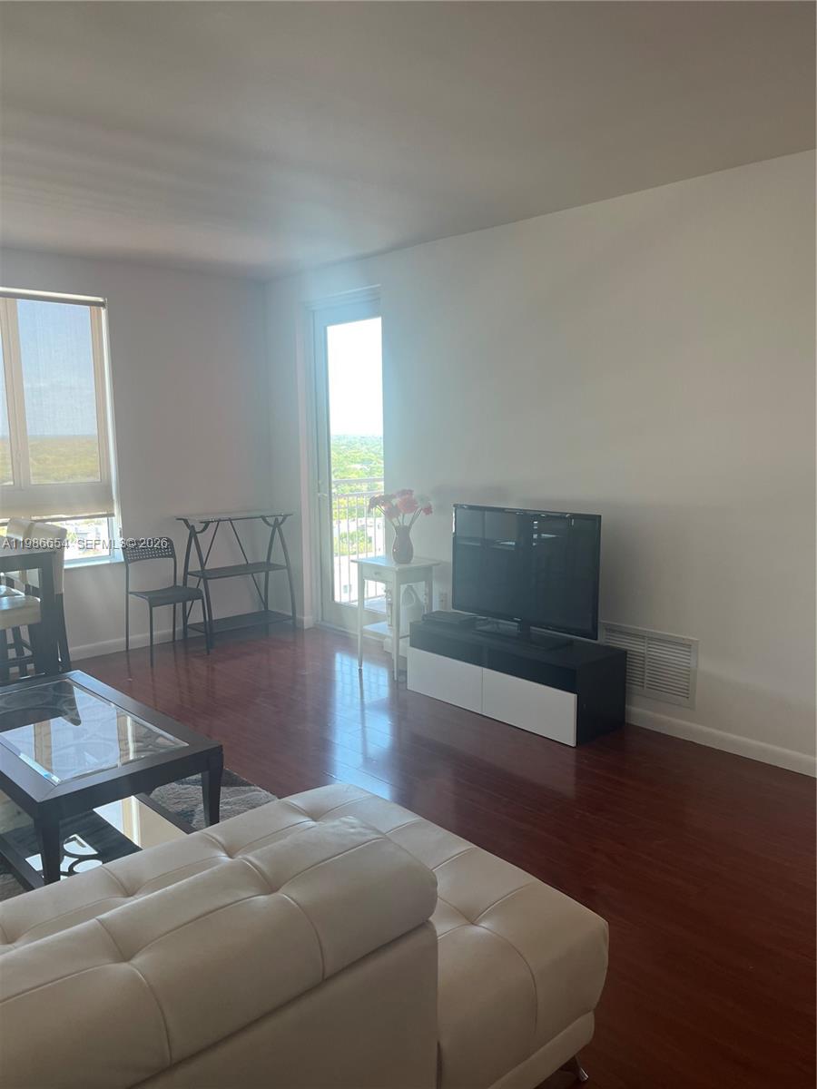 A living room features a white sofa, a television on a stand, and a balcony door — 7350 SW 89th St # 1801S, Miami FL 33156, MIAMI, FL