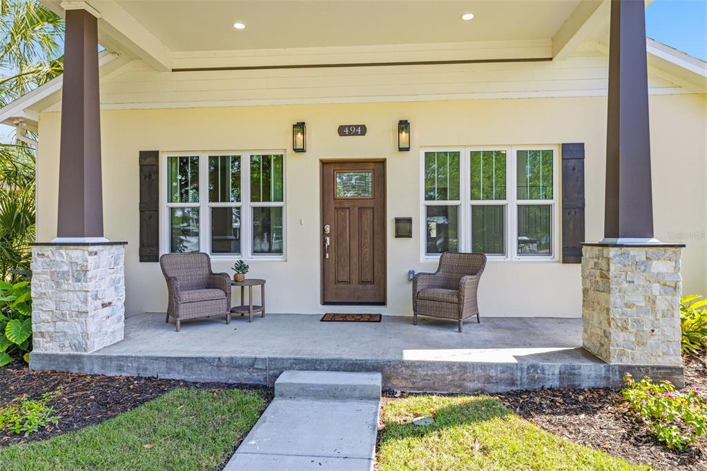 A front porch with two wicker chairs, a wooden door, and stone-based columns — 494 39TH AVENUE N, ST PETERSBURG, FL