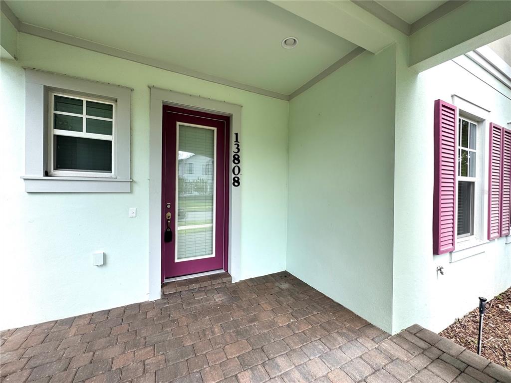 A front entrance features a purple door with a glass insert and brick pavers — 13808 CHAUVIN AVENUE, ORLANDO, FL