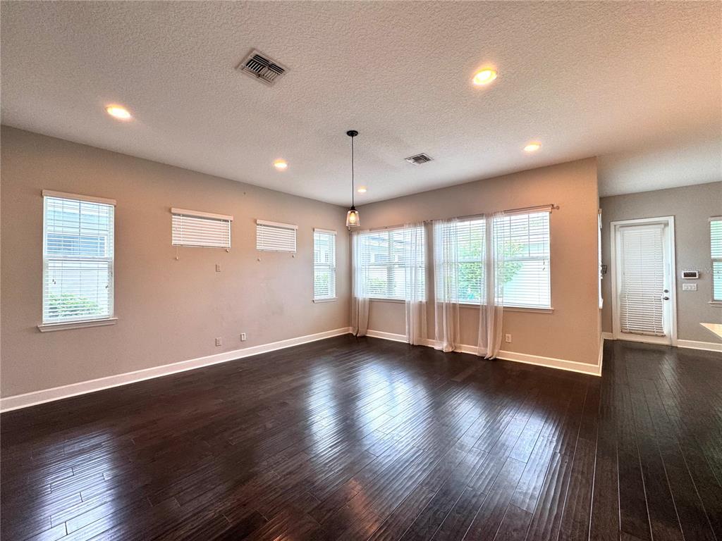 A spacious room with dark hardwood floors, neutral walls, recessed lighting, and multiple windows — 13808 CHAUVIN AVENUE, ORLANDO, FL