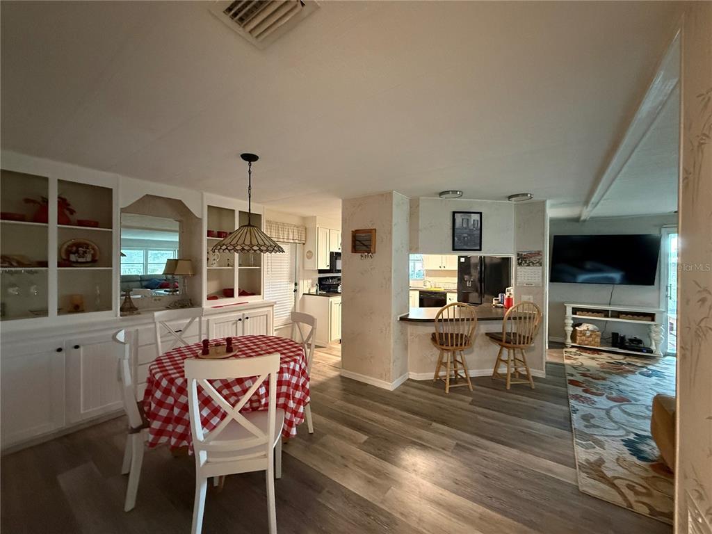 A dining area with a red checkered table sits adjacent to a kitchen breakfast bar — 24 N BOBWHITE ROAD, WILDWOOD, FL