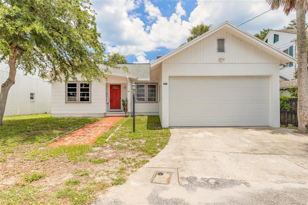 A single-story white house with a red front door, a garage, and a brick walkway — 255 LEXINGTON DRIVE, DAYTONA BEACH, FL