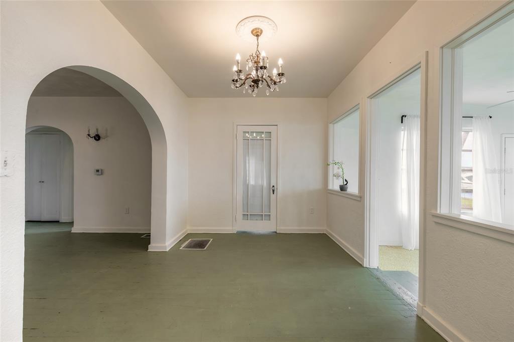 An interior view of a room with green floors, an arched doorway, and a chandelier — 255 LEXINGTON DRIVE, DAYTONA BEACH, FL