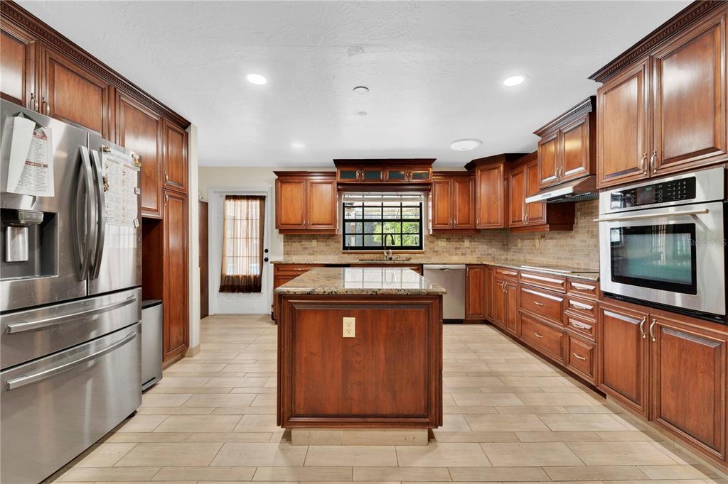 A kitchen with wood cabinets, stainless steel appliances, a center island, and tile flooring — 2456 DANFORTH ROAD, SPRING HILL, FL
