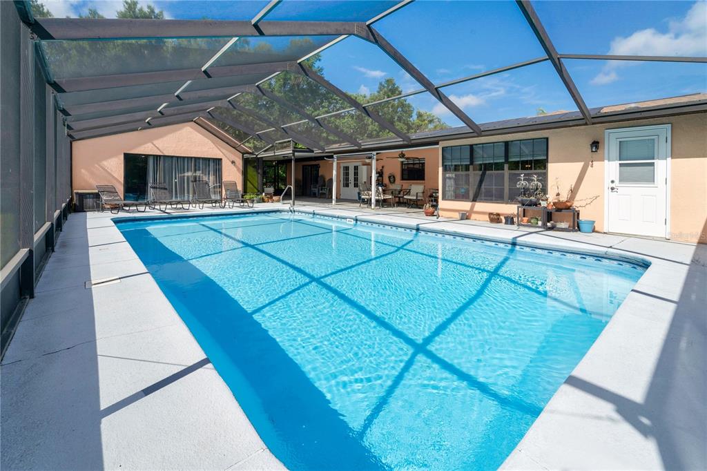 A rectangular swimming pool is enclosed by a screened lanai with a concrete deck — 2456 DANFORTH ROAD, SPRING HILL, FL