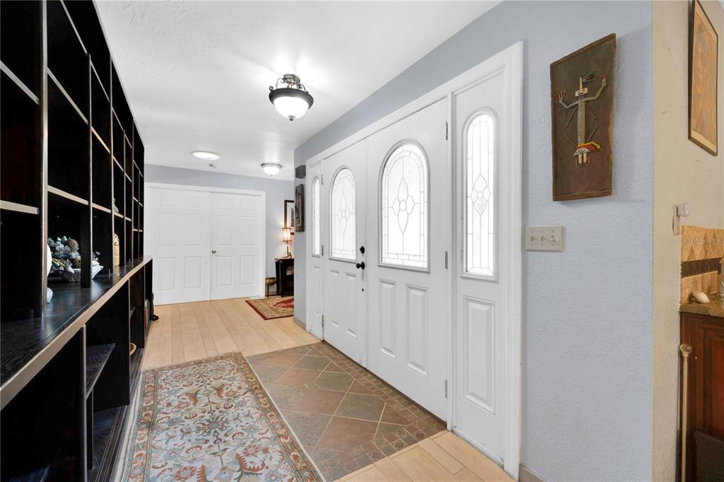An entryway features a tiled floor, a large built-in bookshelf, and a white double door — 2456 DANFORTH ROAD, SPRING HILL, FL