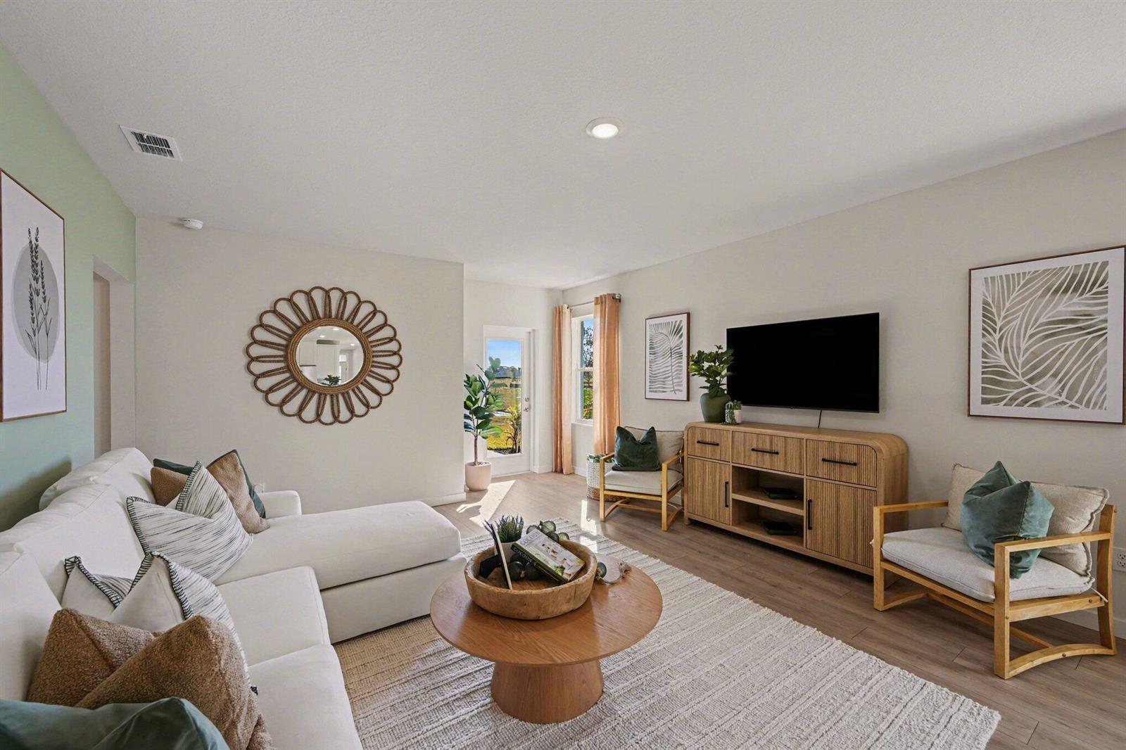 A living room features a white sectional sofa, a round wooden coffee table, and two chairs — 9633 Venetian Square, Vero Beach FL 32966, VERO BEACH, FL