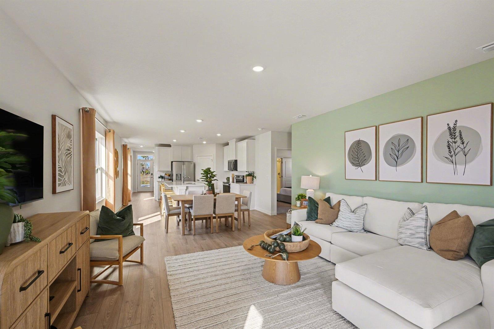 An open-concept living room and kitchen feature light wood flooring and a sage green wall — 9633 Venetian Square, Vero Beach FL 32966, VERO BEACH, FL