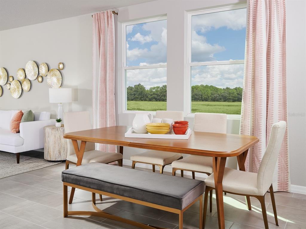 A dining area with a wooden table, chairs, a bench, and windows overlooking a field — 3442 MOSCATO DRIVE, BROOKSVILLE, FL
