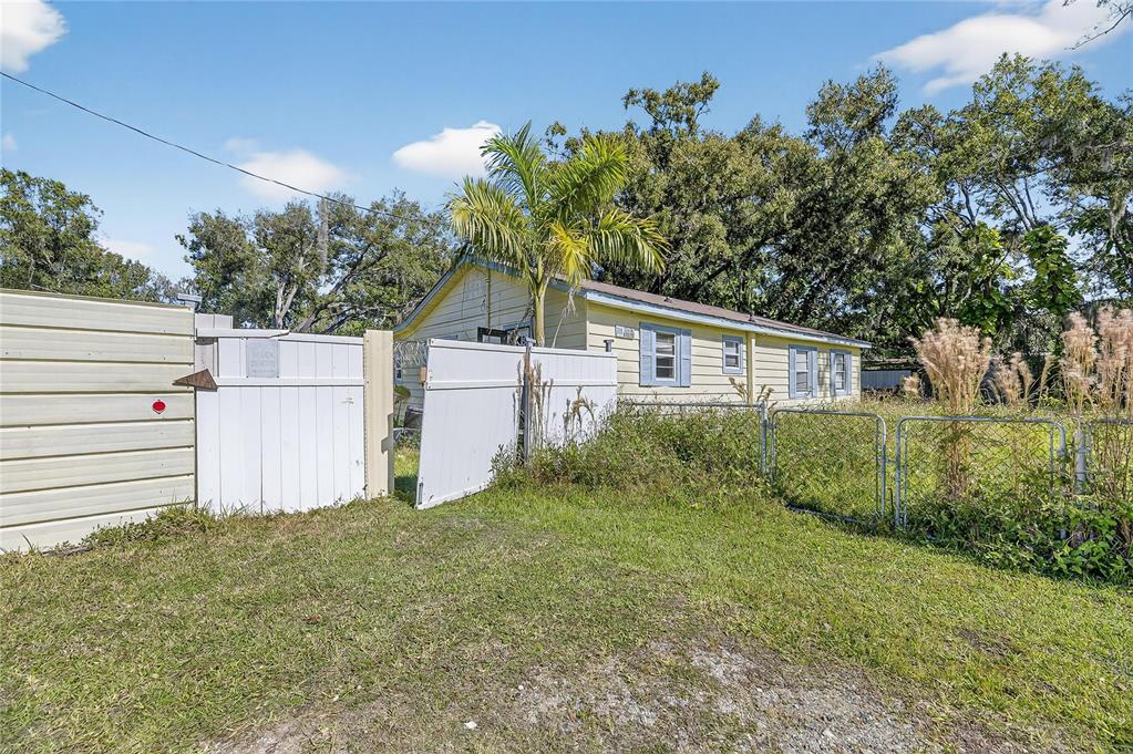 A yellow house with a white fence and a palm tree in the yard — 311 S WEBB ROAD, PLANT CITY, FL