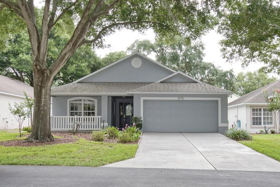 A gray single-story house with a two-car garage, a front porch, and a large tree — 3605 WESTERHAM DR, CLERMONT, FL