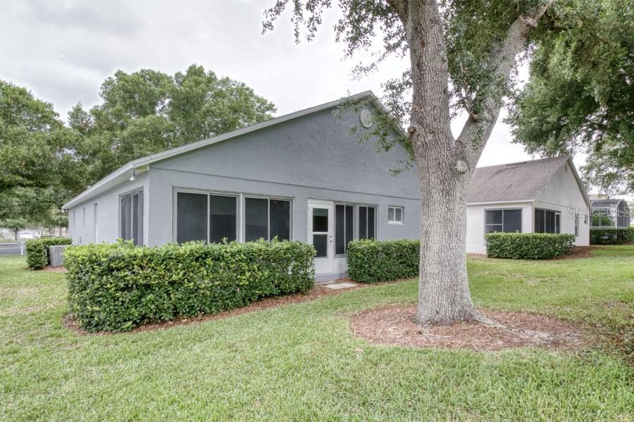 The exterior of a gray house features a screened-in porch and a large shade tree — 3605 WESTERHAM DR, CLERMONT, FL