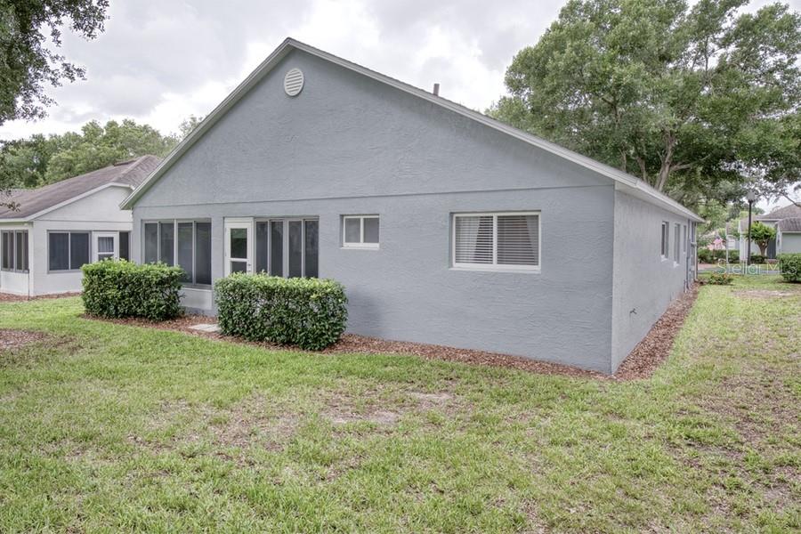 A gray stucco house exterior features a screened-in porch and a small backyard lawn — 3605 WESTERHAM DR, CLERMONT, FL