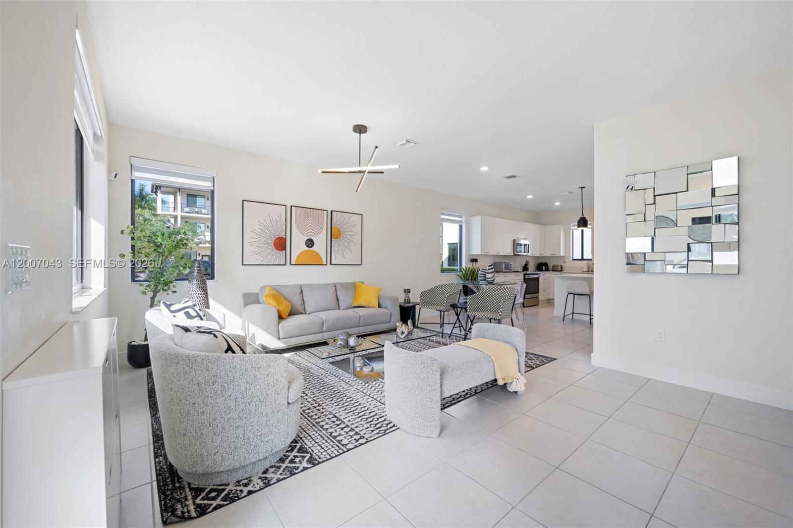 A modern living room with gray furniture, a patterned rug, and an open kitchen — 8387 NW 43rd St, Doral FL 33166, DORAL, FL