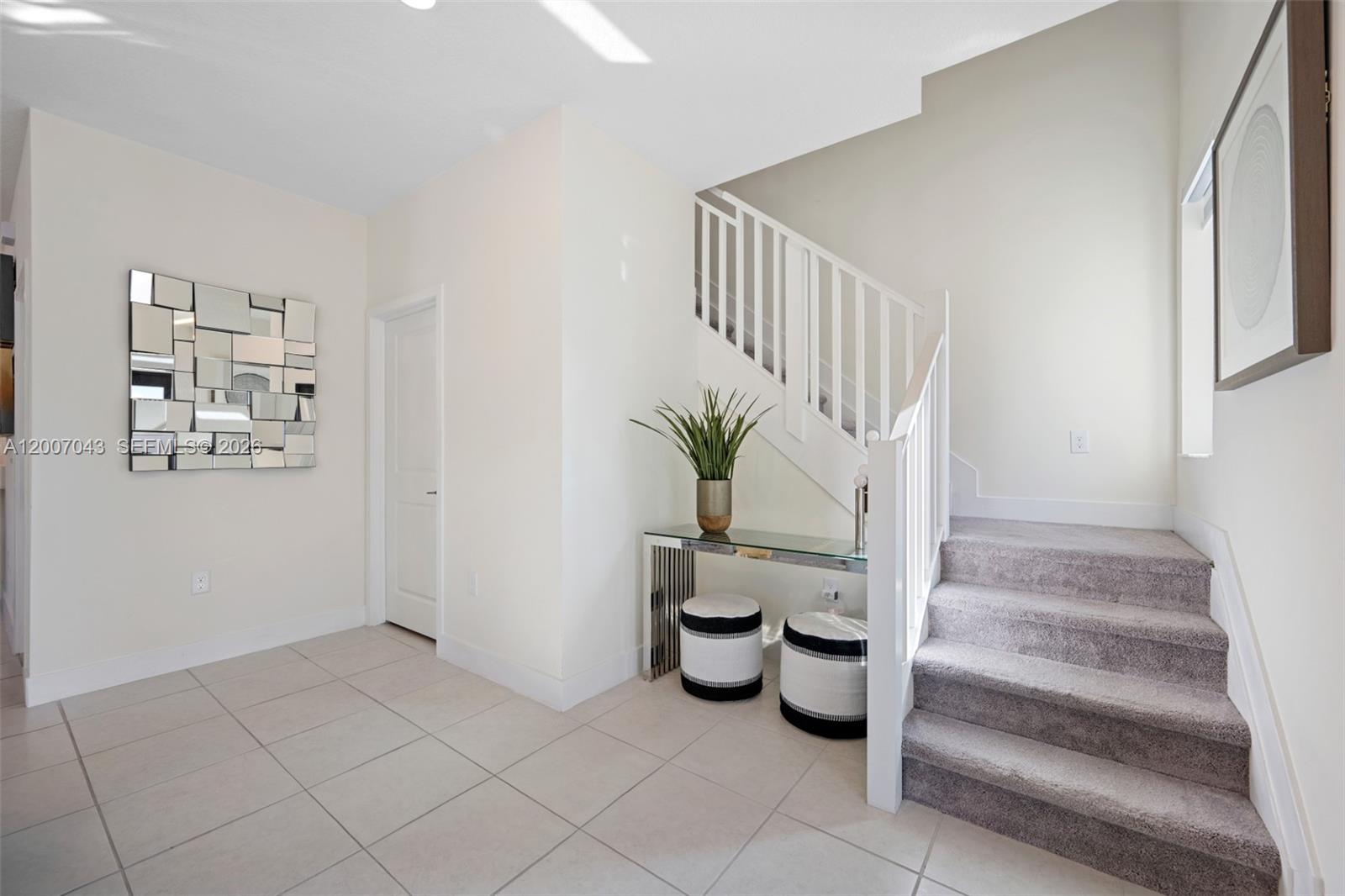 A bright entryway features tiled floors, a staircase with gray carpeting, and a mirrored wall — 8387 NW 43rd St, Doral FL 33166, DORAL, FL